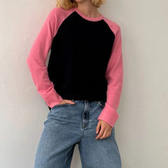 Person wearing a black and pink long-sleeve shirt with blue jeans 