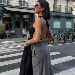 A woman wearing a black backless bodysuit with high-waisted jeans, showcasing its versatility and edgy style.