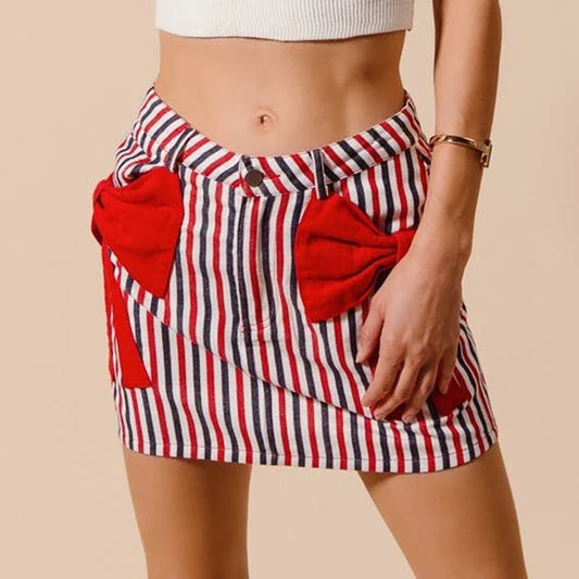 Red, white, and blue striped skirt with red bow pockets on a beige background