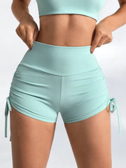 A woman wearing high-waist ruched athletic shorts in a mint green color.