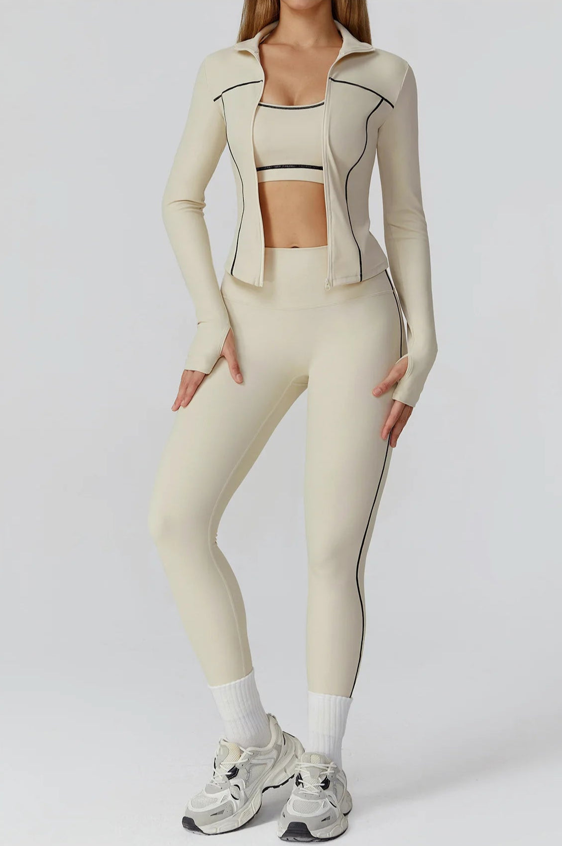 A woman wearing a fitted zip-front athletic jacket in a neutral apricot color.