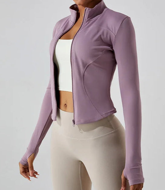 A woman wearing a fitted zip-up workout jacket in a lavender color.